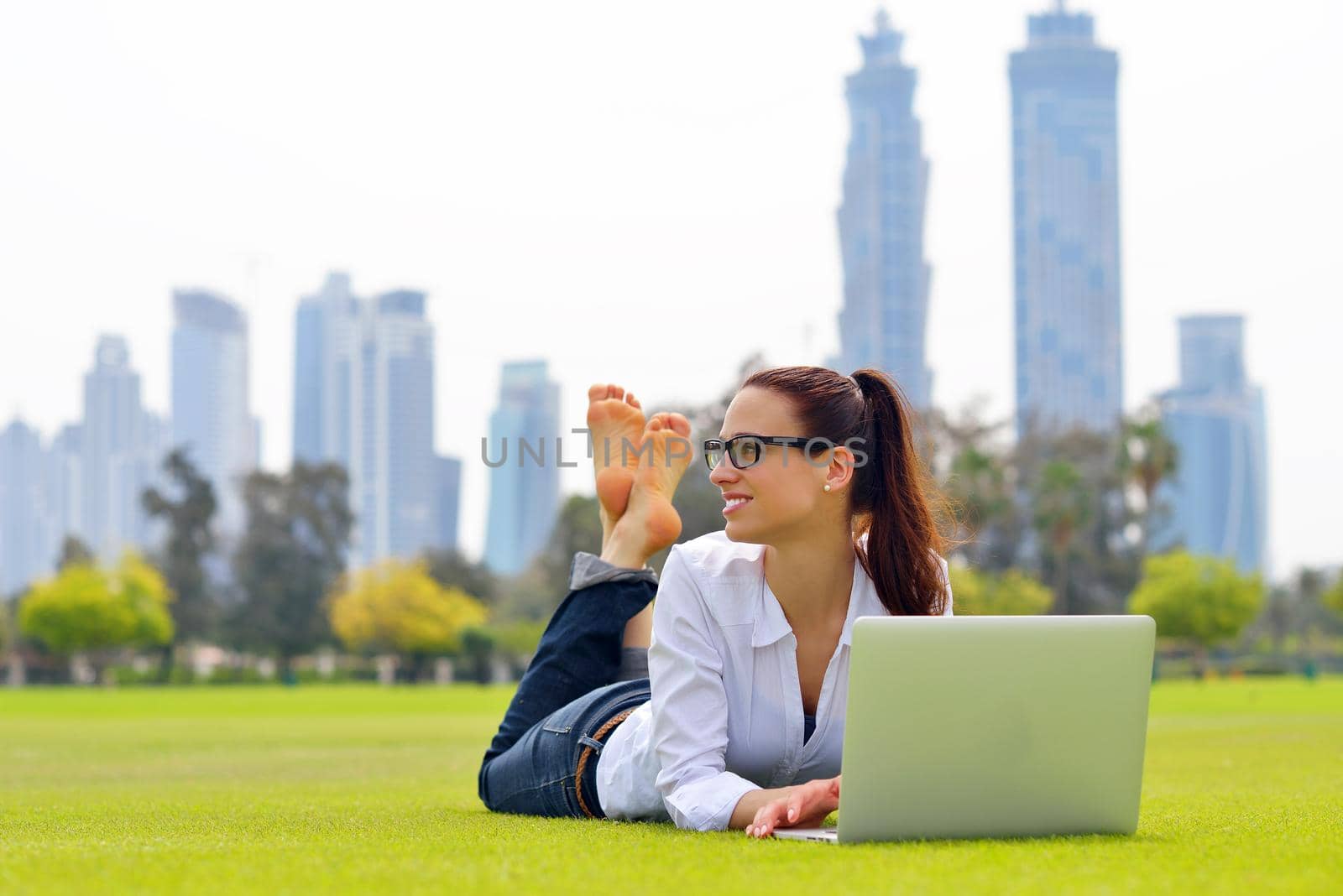 happy young student woman with laptop in city park study