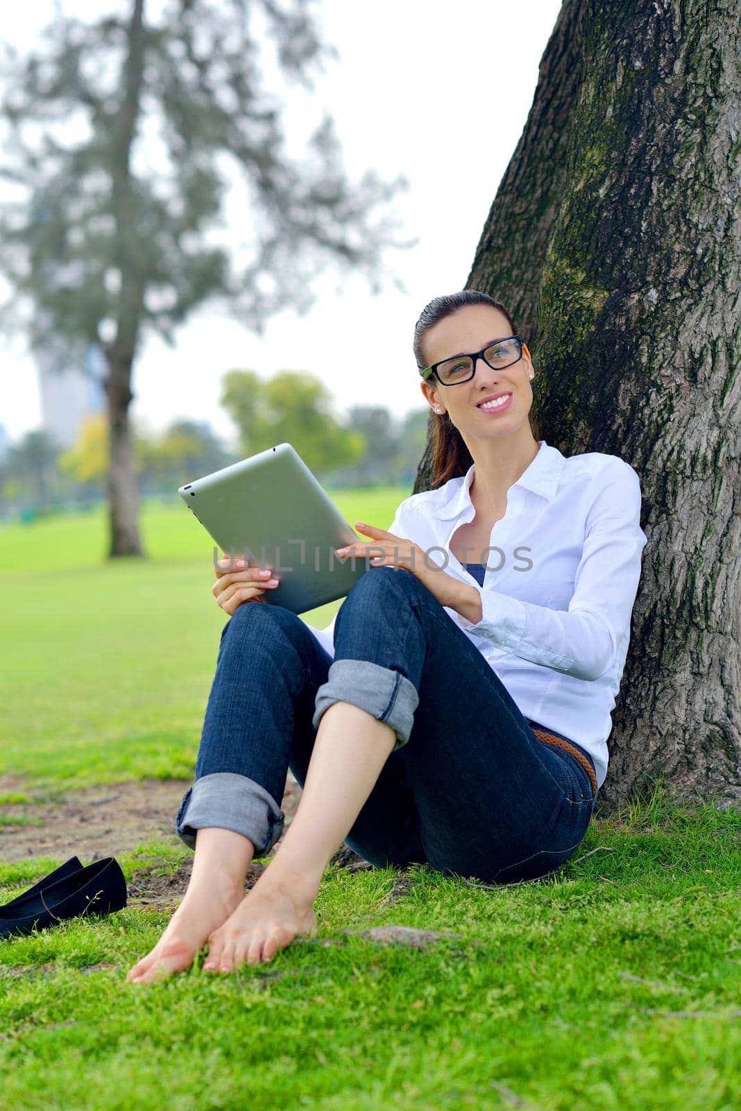 Beautiful young woman with  tablet in park by dotshock