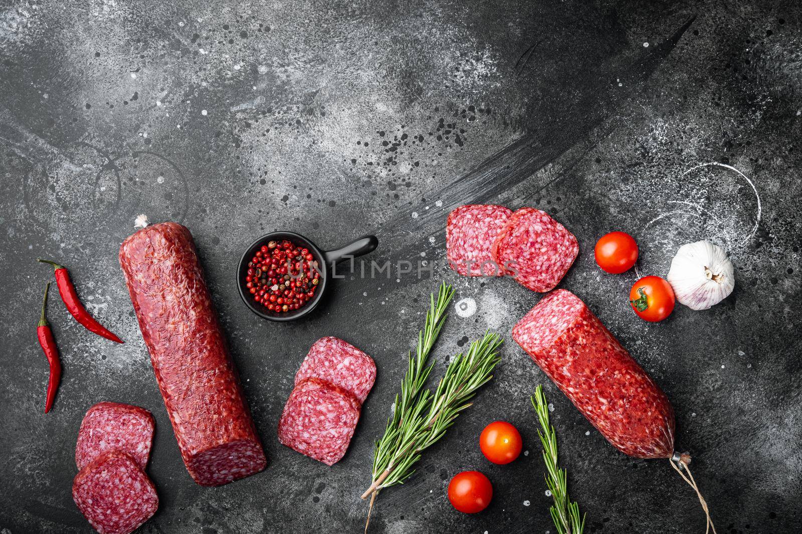 Salami with herbs and spices set, on black dark stone table background, top view flat lay, with copy space for text