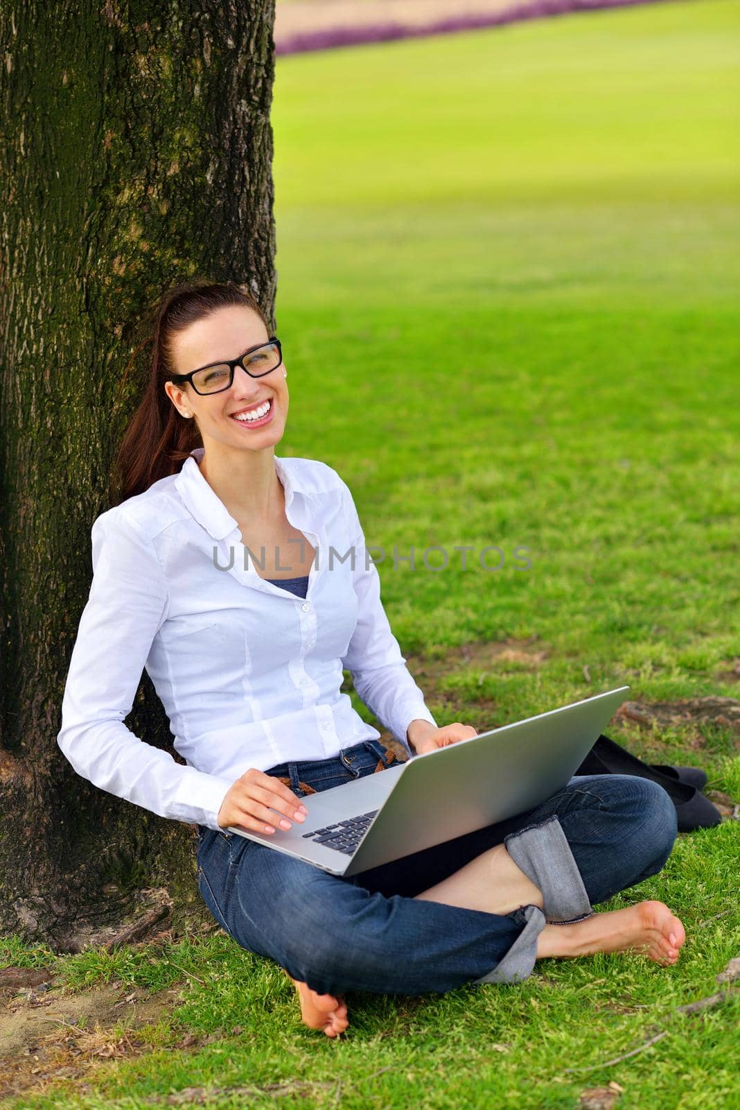 happy young student woman with laptop in city park study