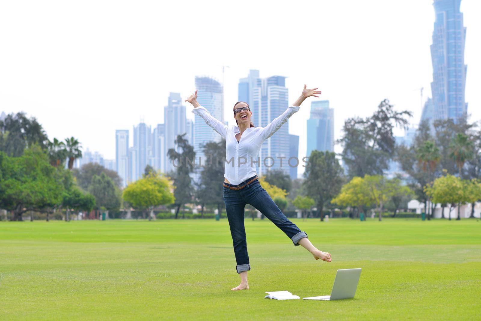 happy young student woman with laptop in city park study