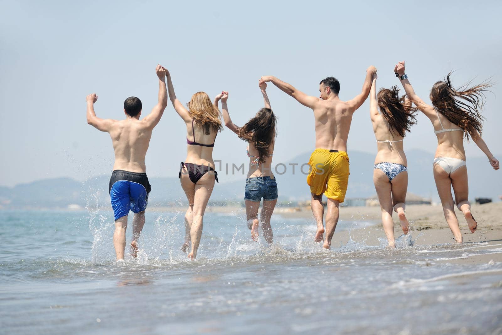 happy young  people group have fun on beach by dotshock