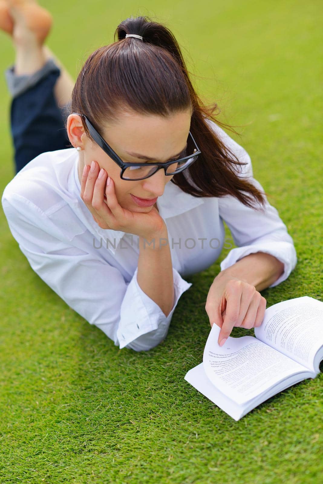 Young woman reading a book in the park by dotshock