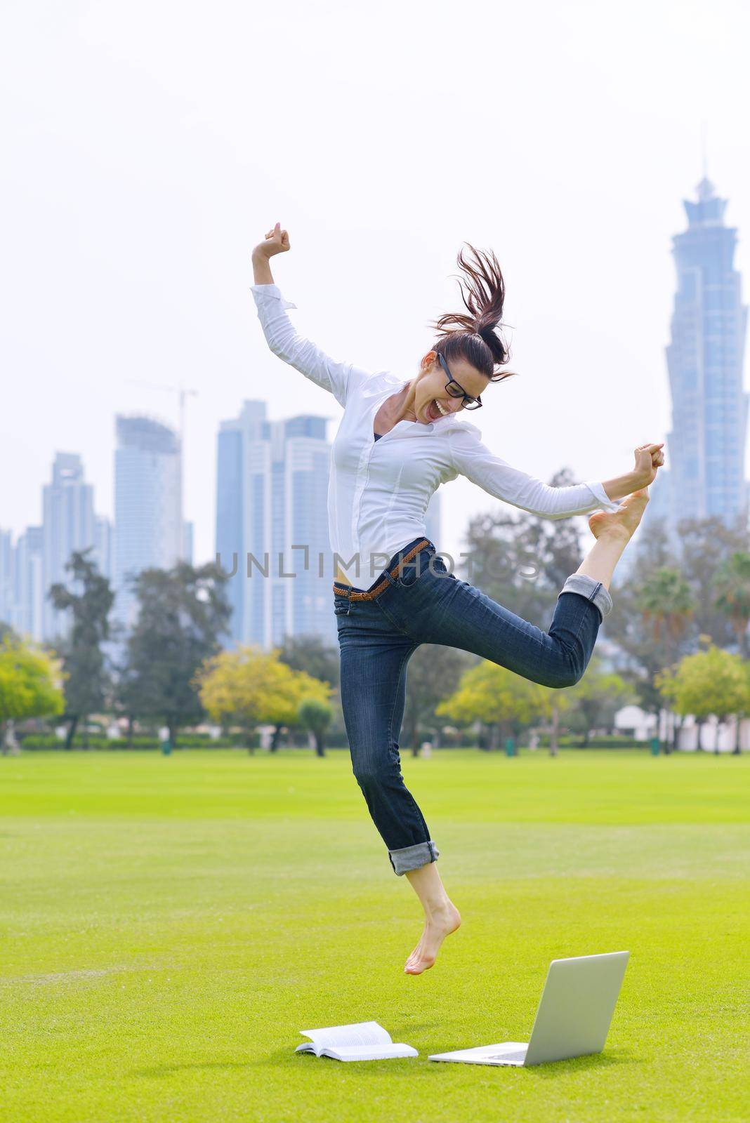 happy young student woman with laptop in city park study