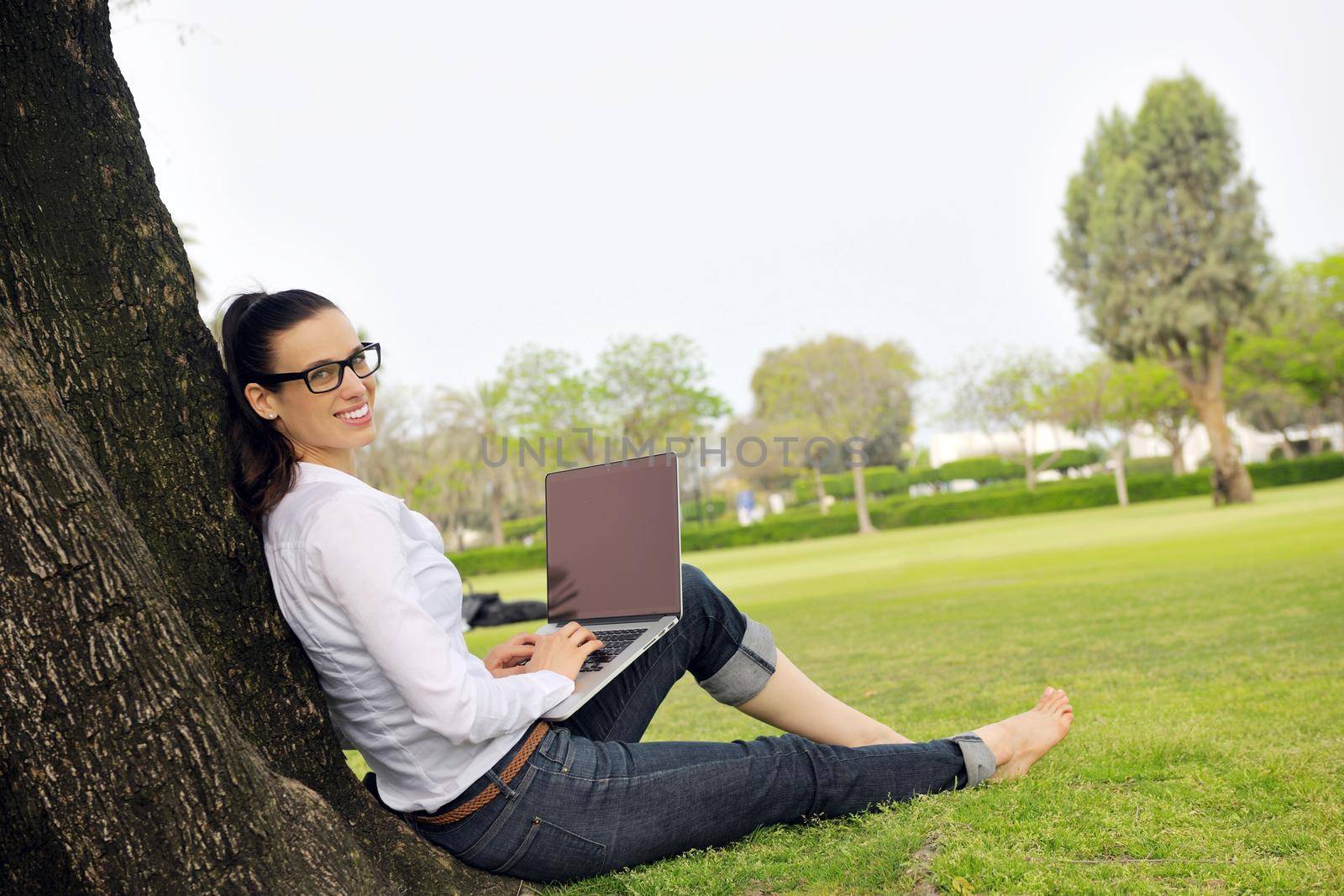 happy young student woman with laptop in city park study