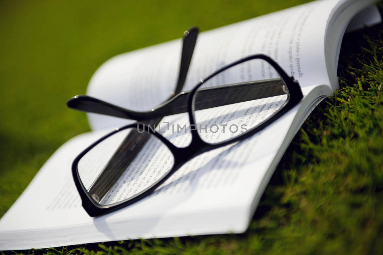 Glasses on a book outside with grass inbbacground, education relax and study concept