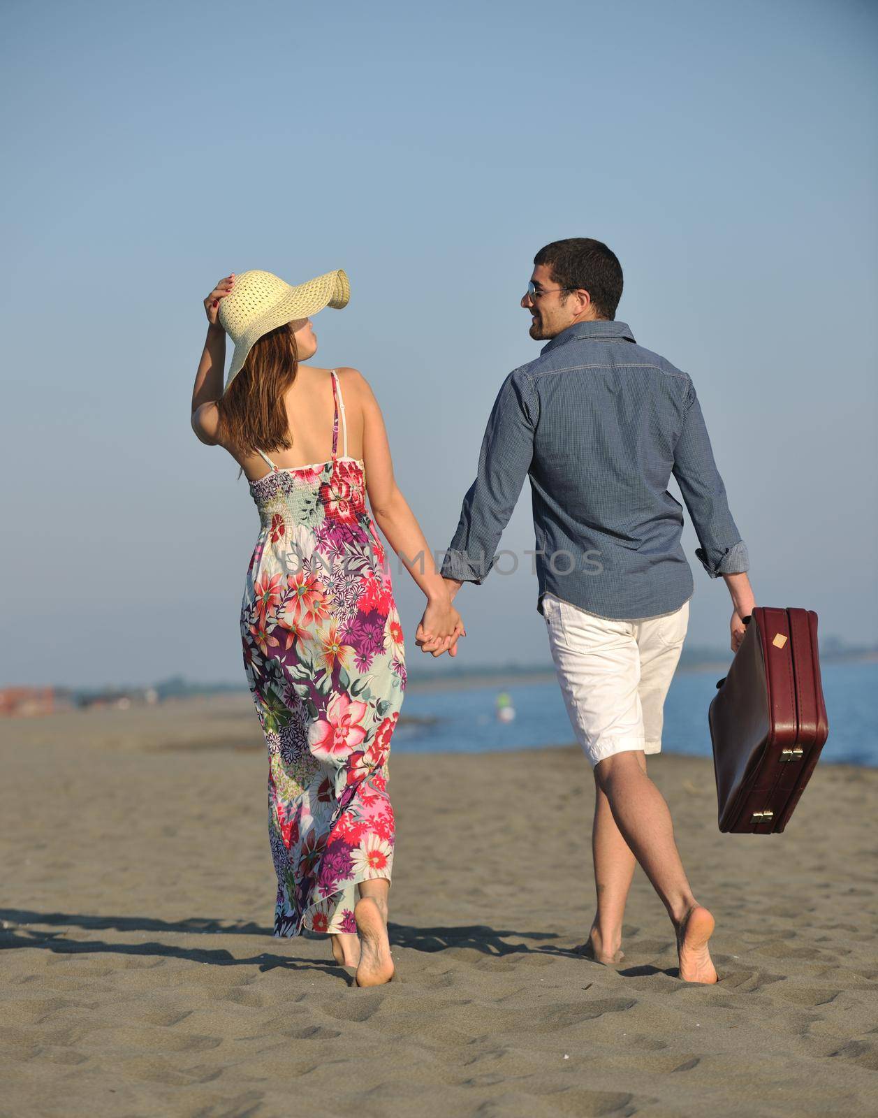 couple on beach with travel bag representing freedom and funy honeymoon concept