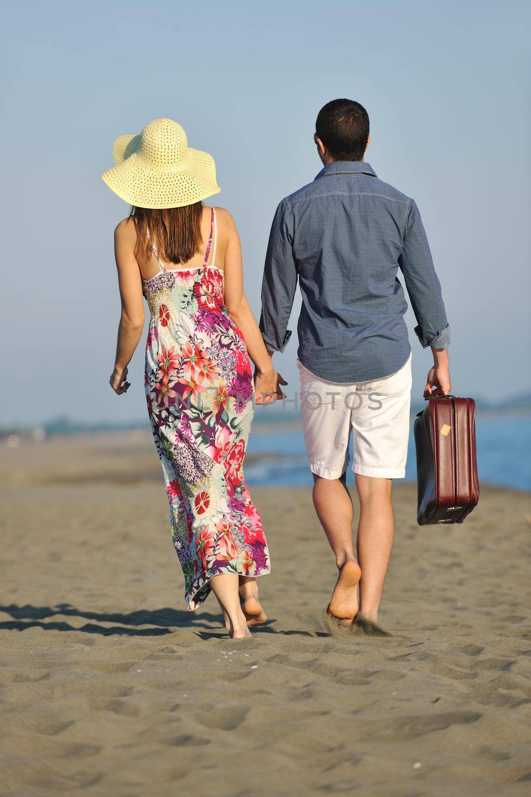 couple on beach with travel bag representing freedom and funy honeymoon concept