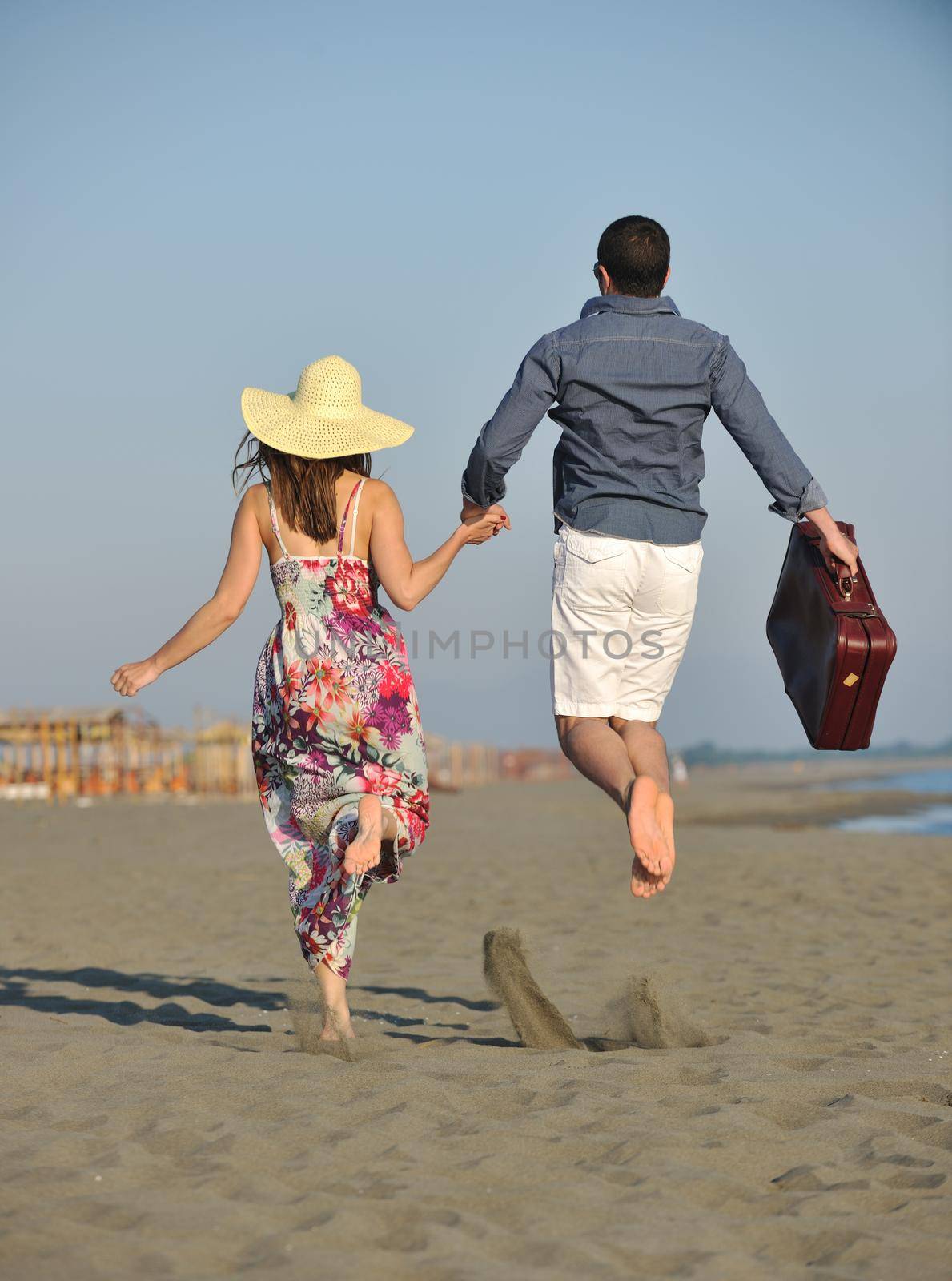couple on beach with travel bag by dotshock