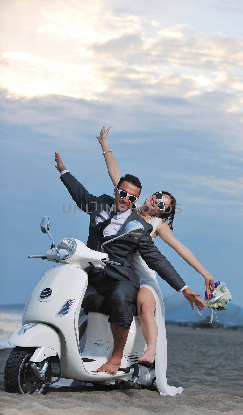 wedding sce of bride and groom just married couple on the beach ride white scooter and have fun