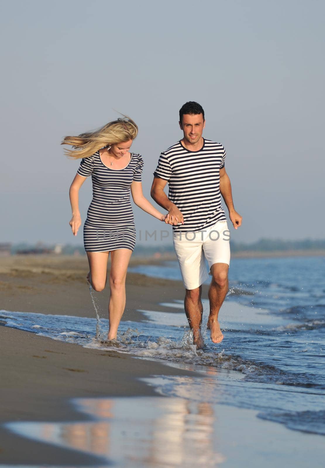 happy young couple have romantic time on beach at sunset