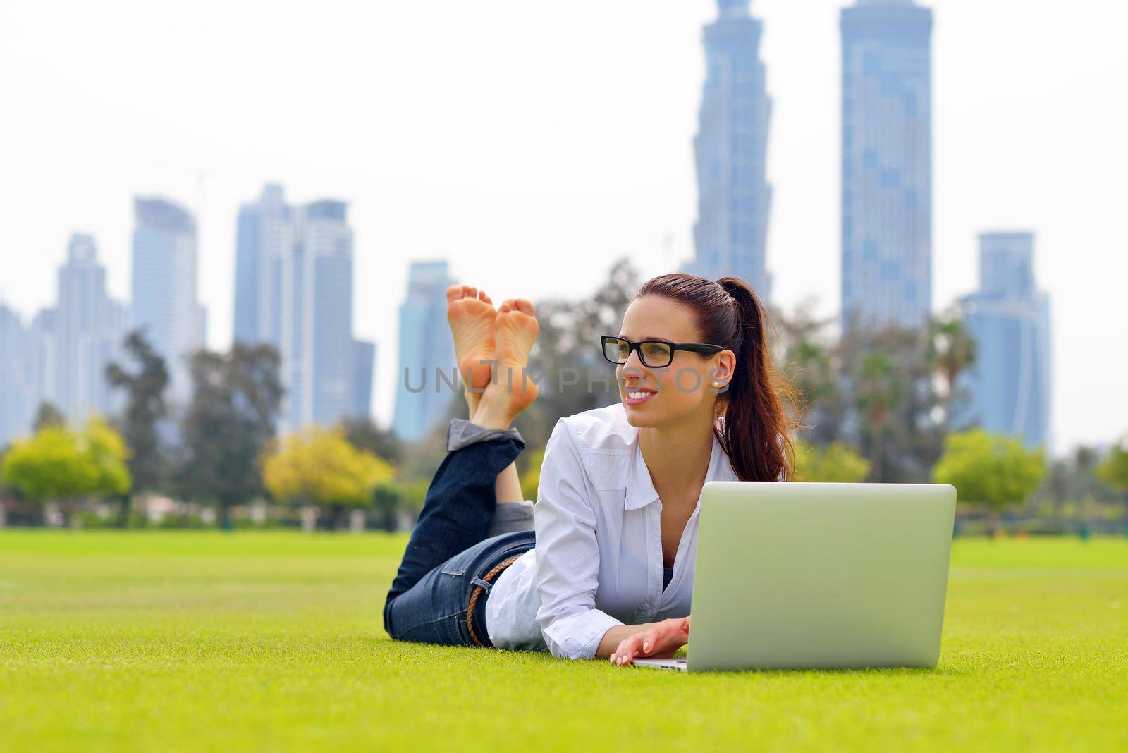 happy young student woman with laptop in city park study