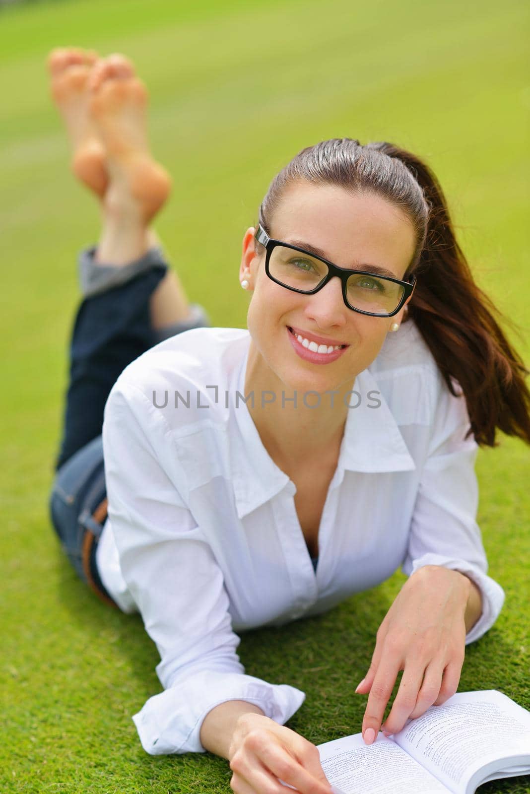 Young woman reading a book in the park by dotshock