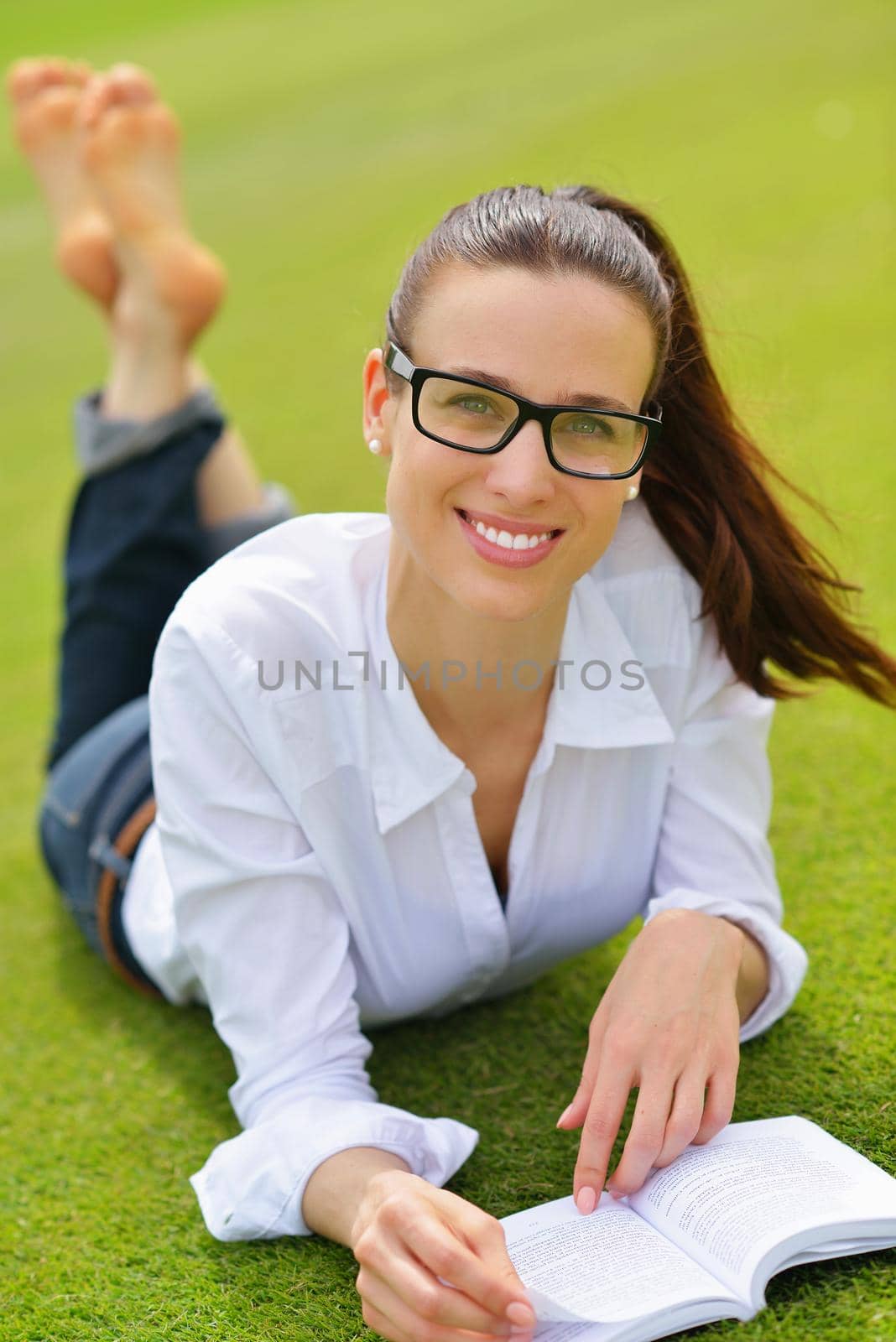 Young woman reading a book in the park by dotshock