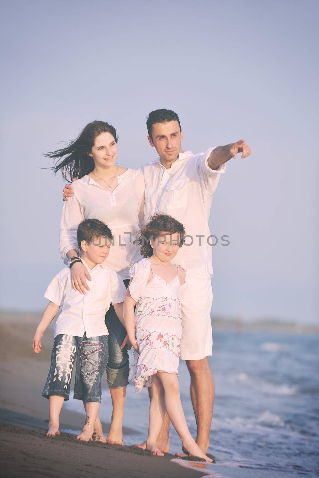 happy young family have fun on beach run and jump  at sunset