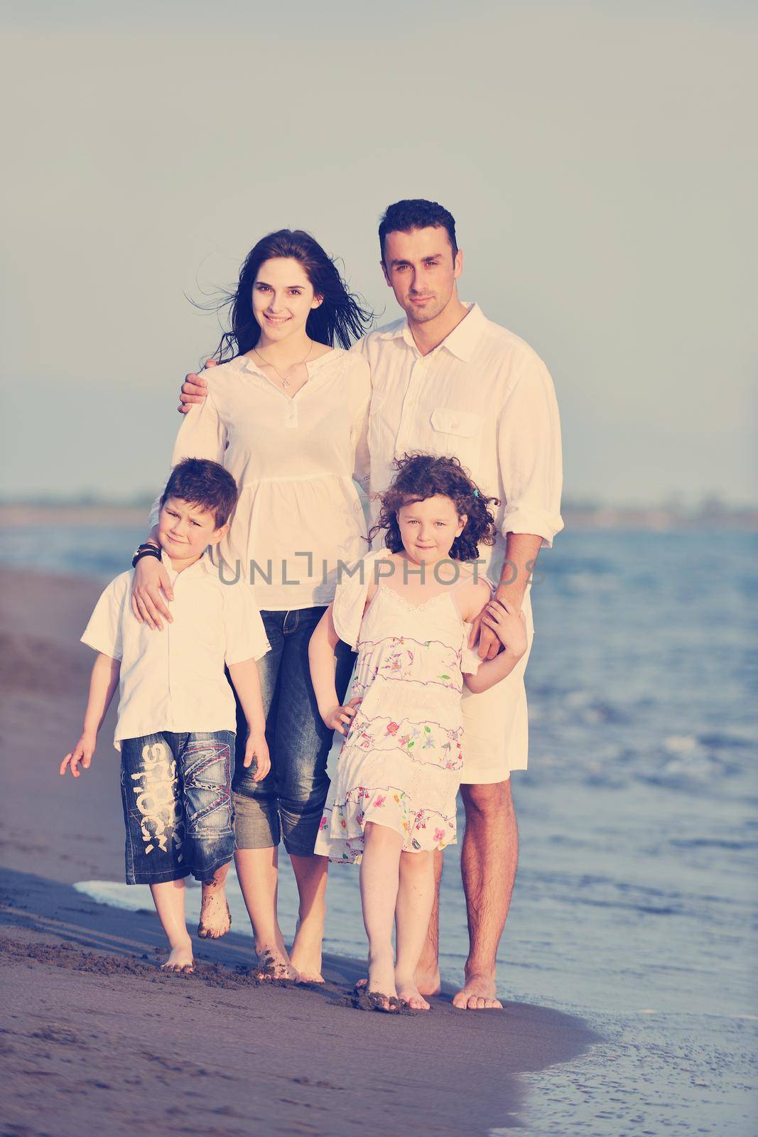 happy young family have fun on beach run and jump  at sunset