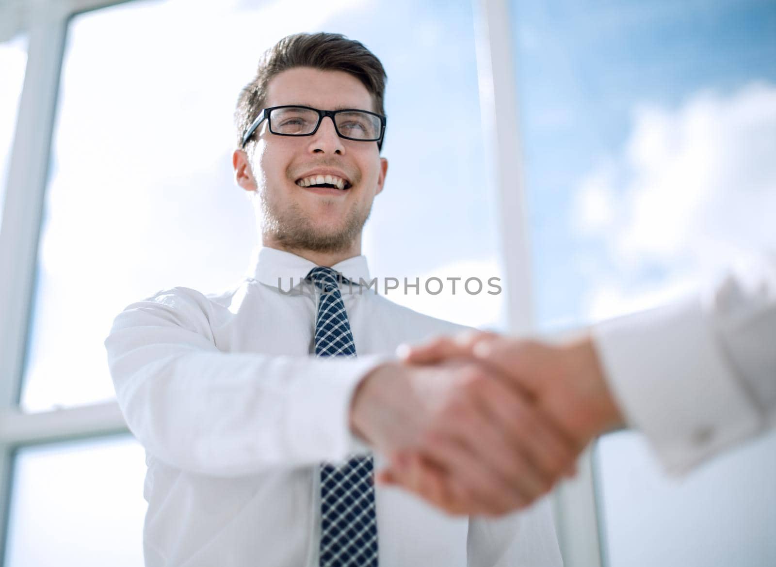 close up.young businessman shaking hands with business partner.photo with copy space