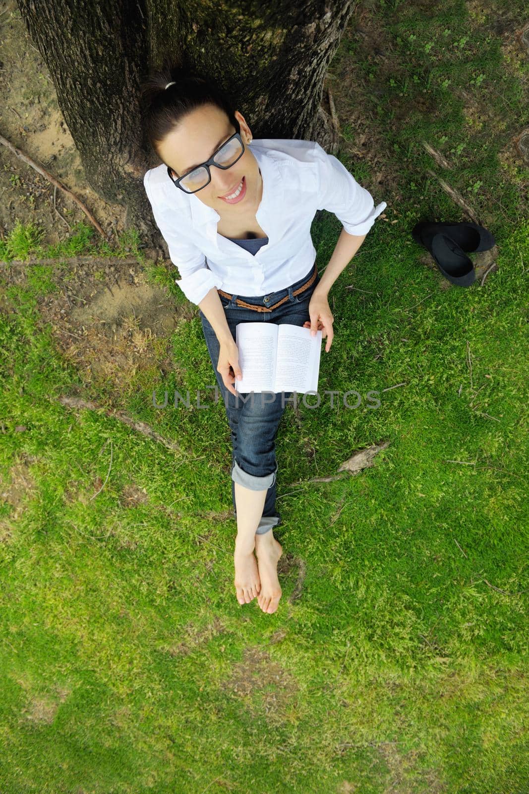 Young woman reading a book in the park by dotshock