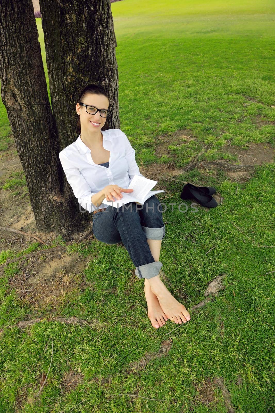 Young woman reading a book in the park by dotshock