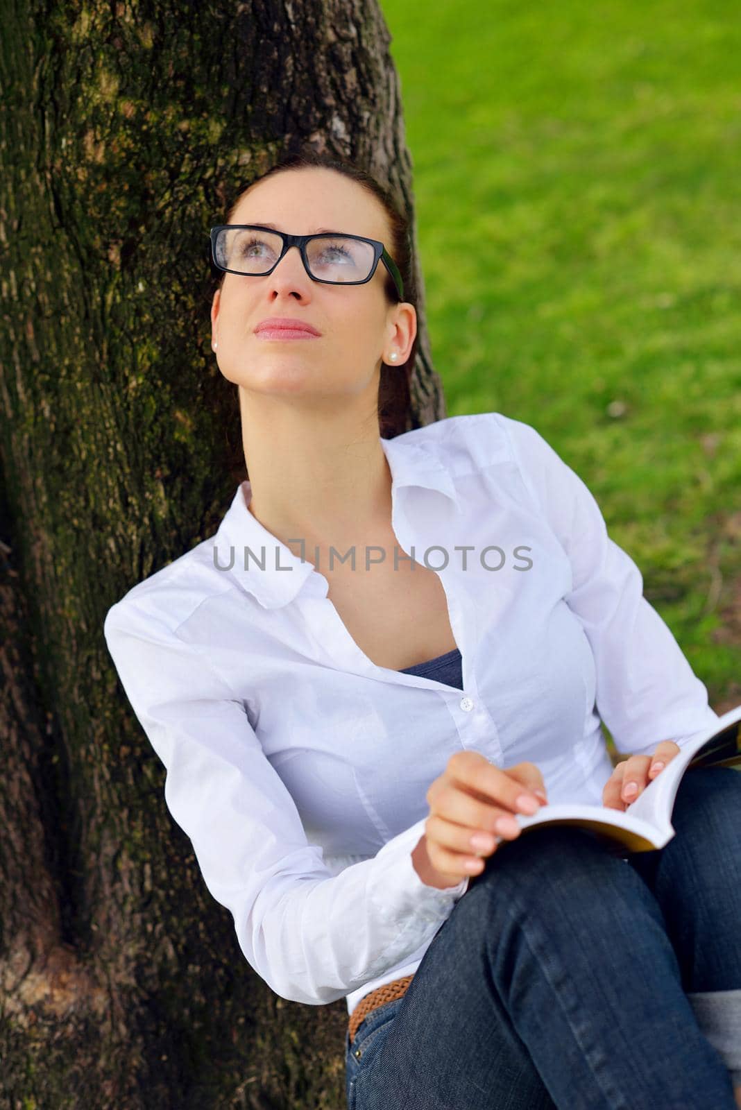 Young woman reading a book in the park by dotshock