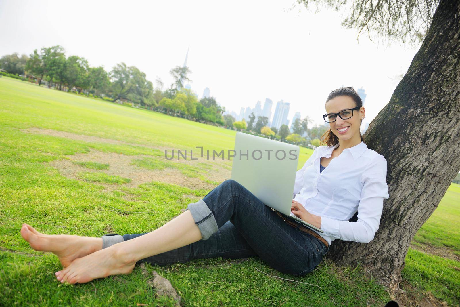 happy young student woman with laptop in city park study