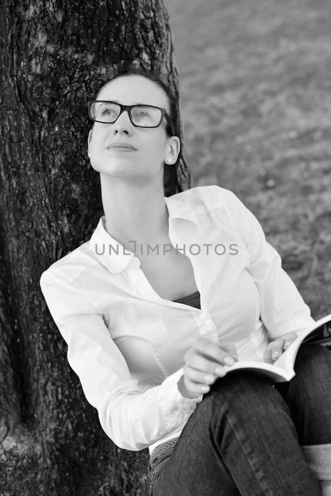 Young woman reading a book in the park by dotshock