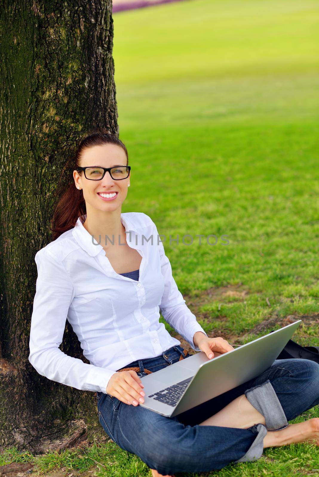 happy young student woman with laptop in city park study