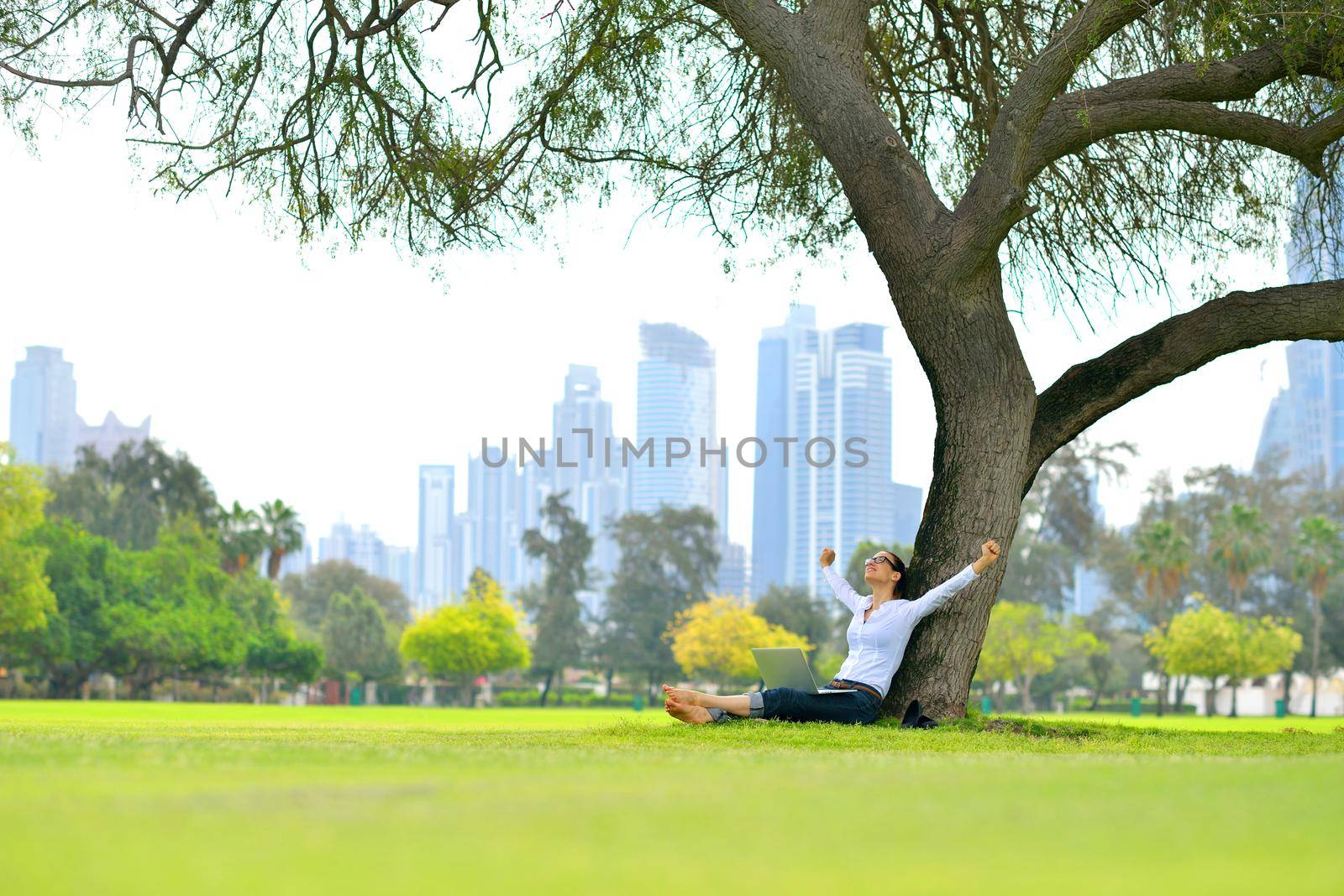 happy young student woman with laptop in city park study