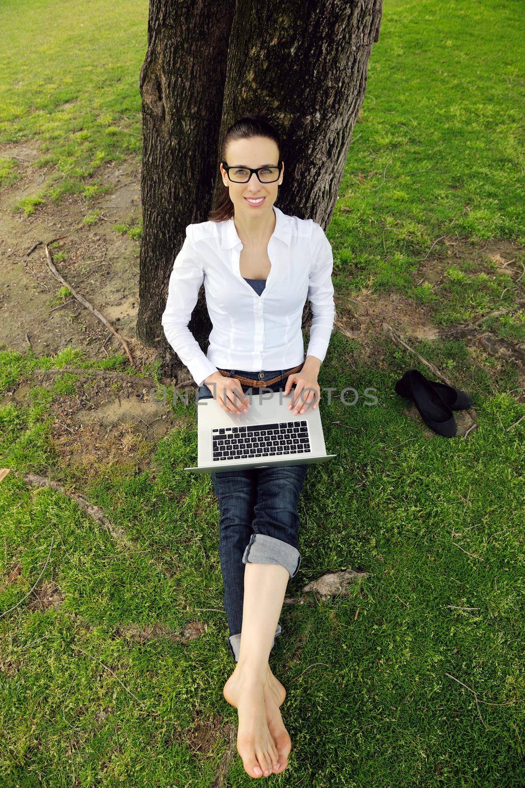 happy young student woman with laptop in city park study