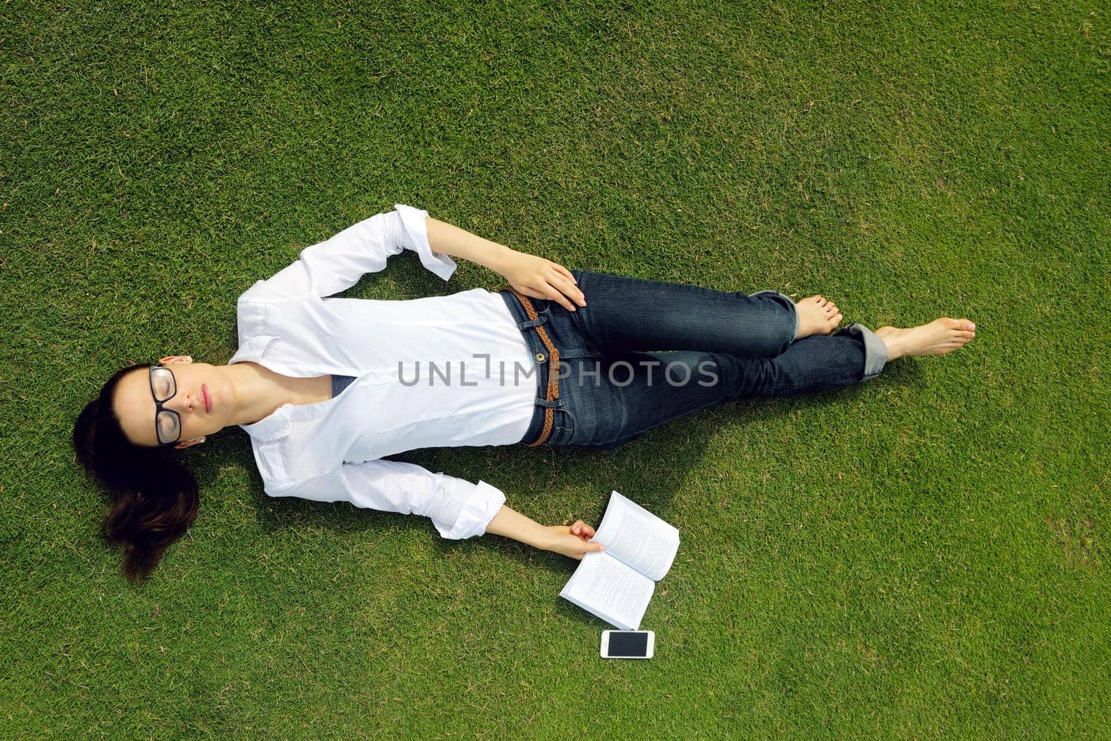 Young woman reading a book in the park by dotshock