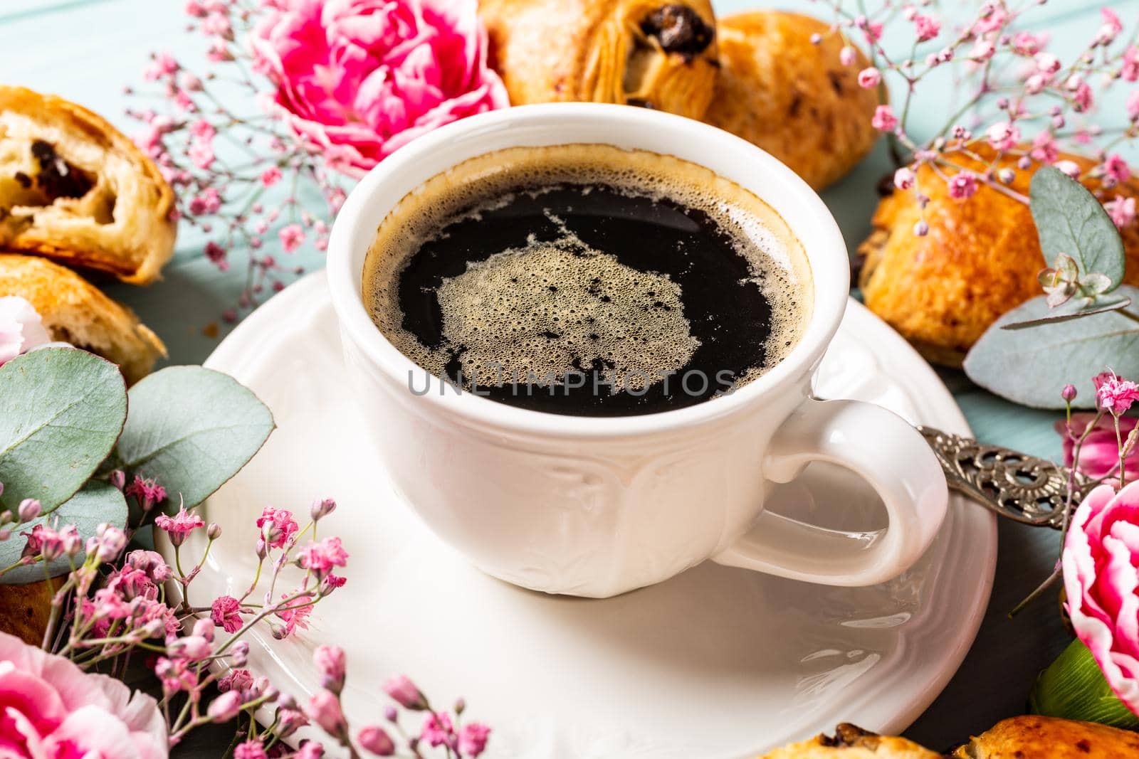 Breakfast with mini fresh croissants bun with chocolate and coffee cup on blue turquoise background.