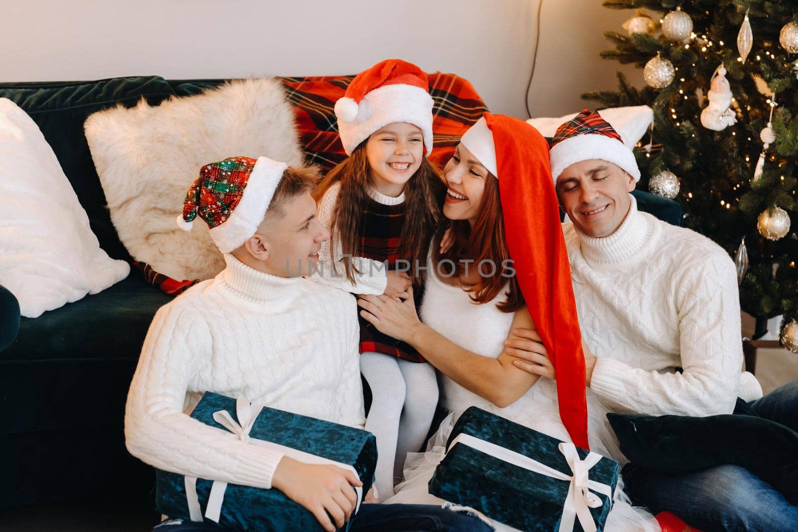 Close-up portrait of a happy family sitting on a sofa near a Christmas tree celebrating a holiday.