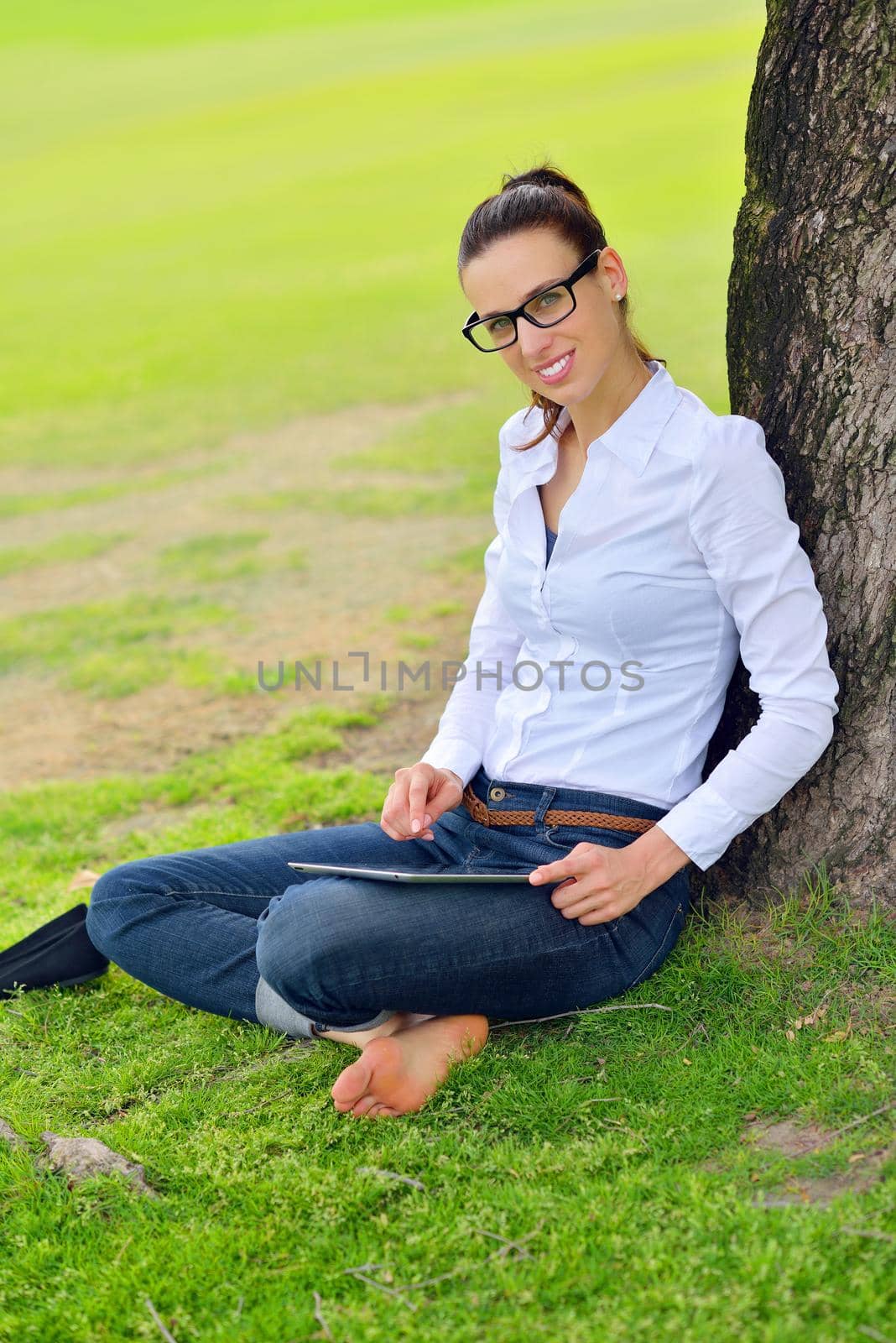 Beautiful young woman with  tablet in park by dotshock