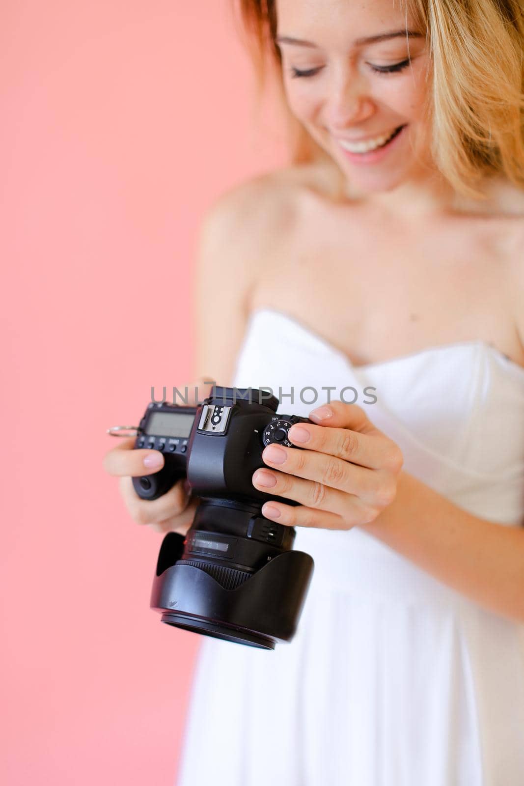 Closeup smiling female photographer with camera in pink monophonic background. by sisterspro