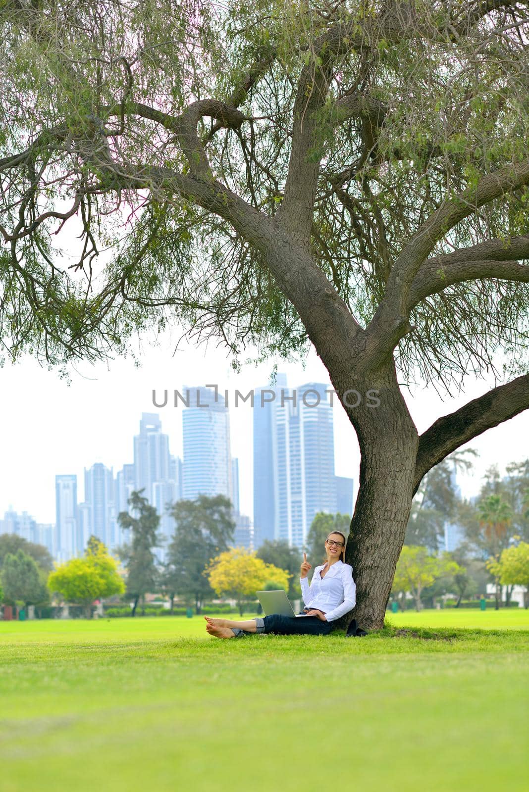 happy young student woman with laptop in city park study