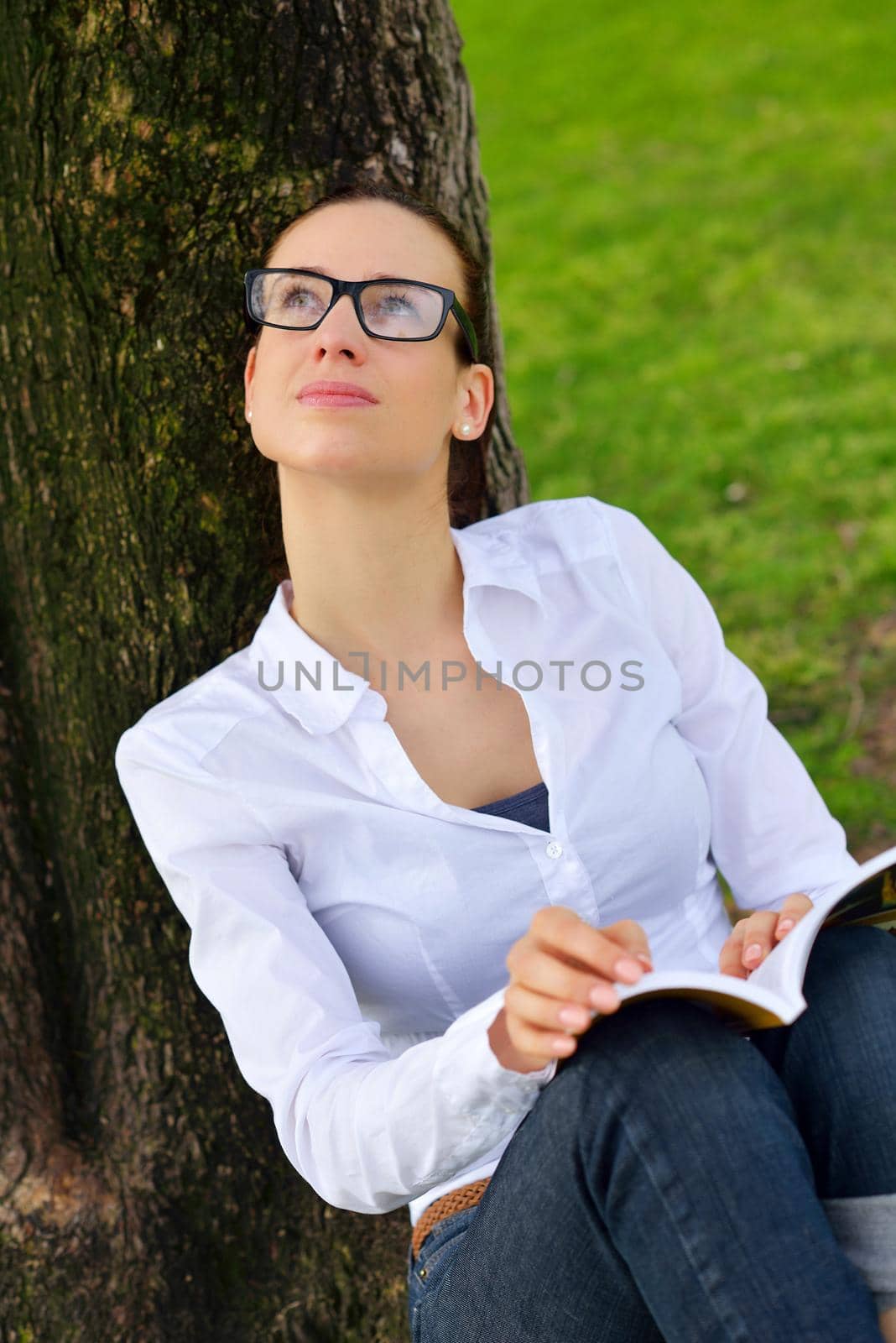 Young woman reading a book in the park by dotshock