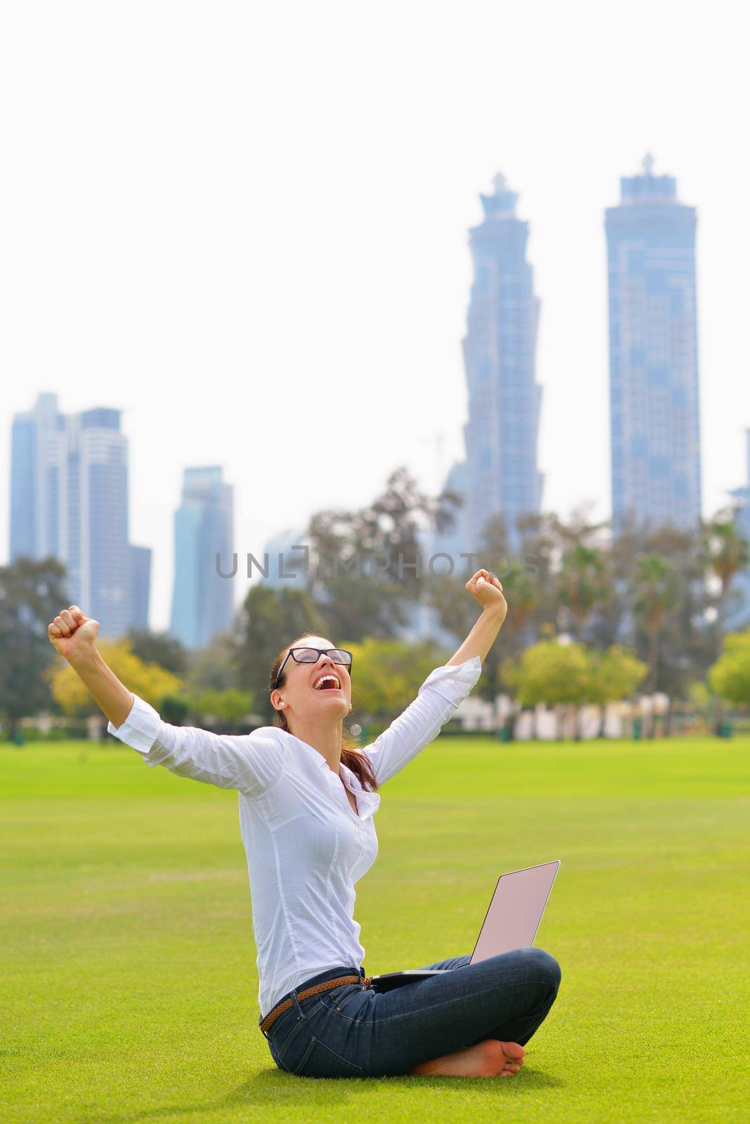 happy young student woman with laptop in city park study