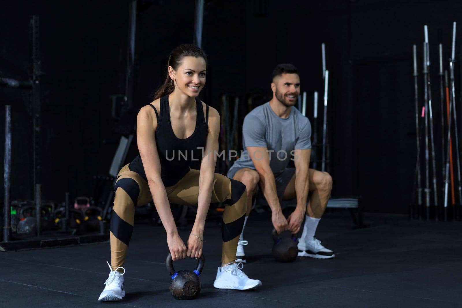 Fit and muscular couple focused on lifting a dumbbell during an exercise class in a gym. by tsyhun