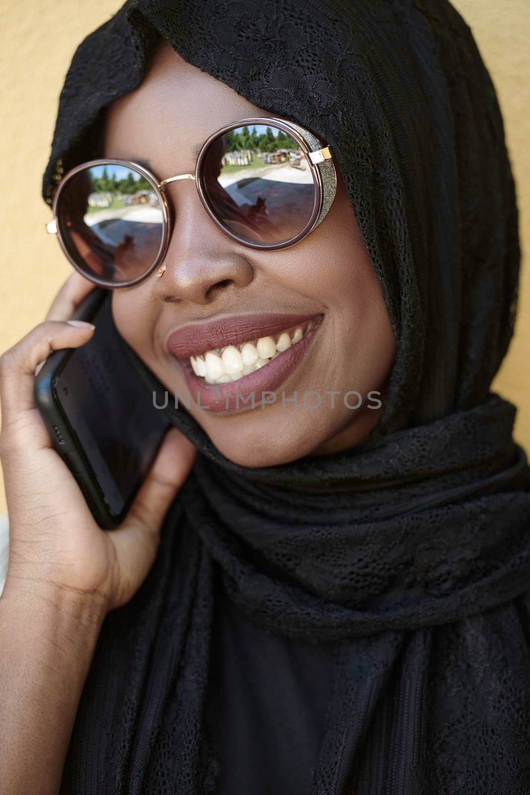 african  woman using smartphone wearing traditional islamic clothes by dotshock