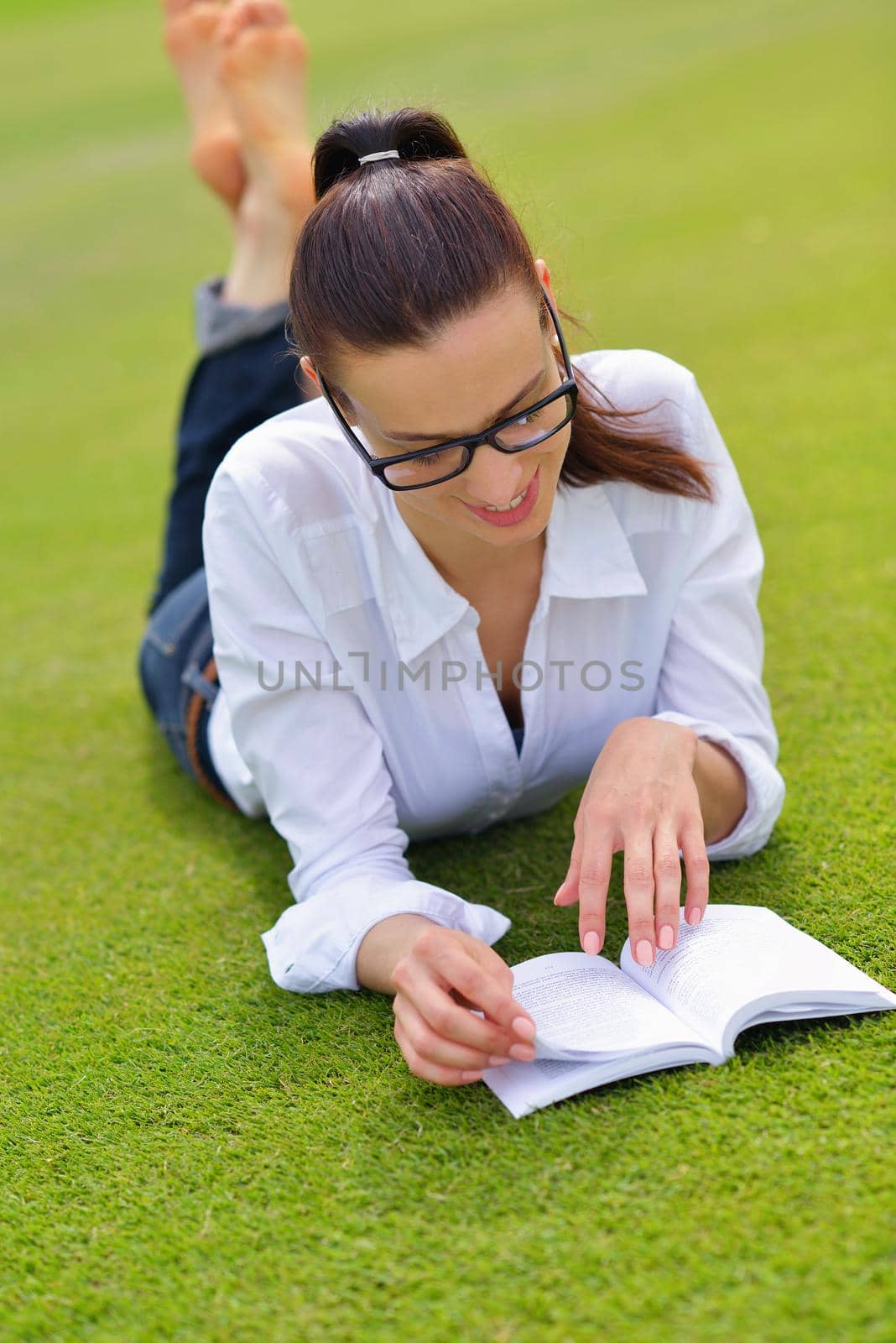 Young woman reading a book in the park by dotshock