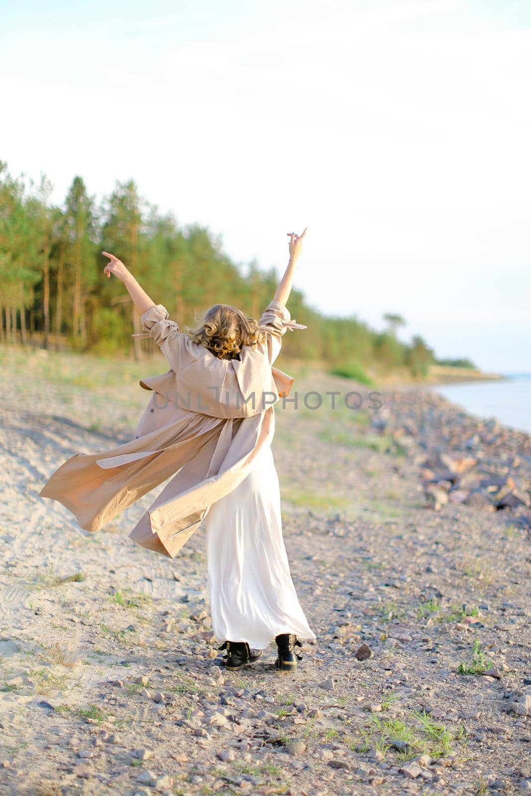 Young girl turning around with raising forefingers up on sea beach. Concept of summer vacations and enjoying freedom.