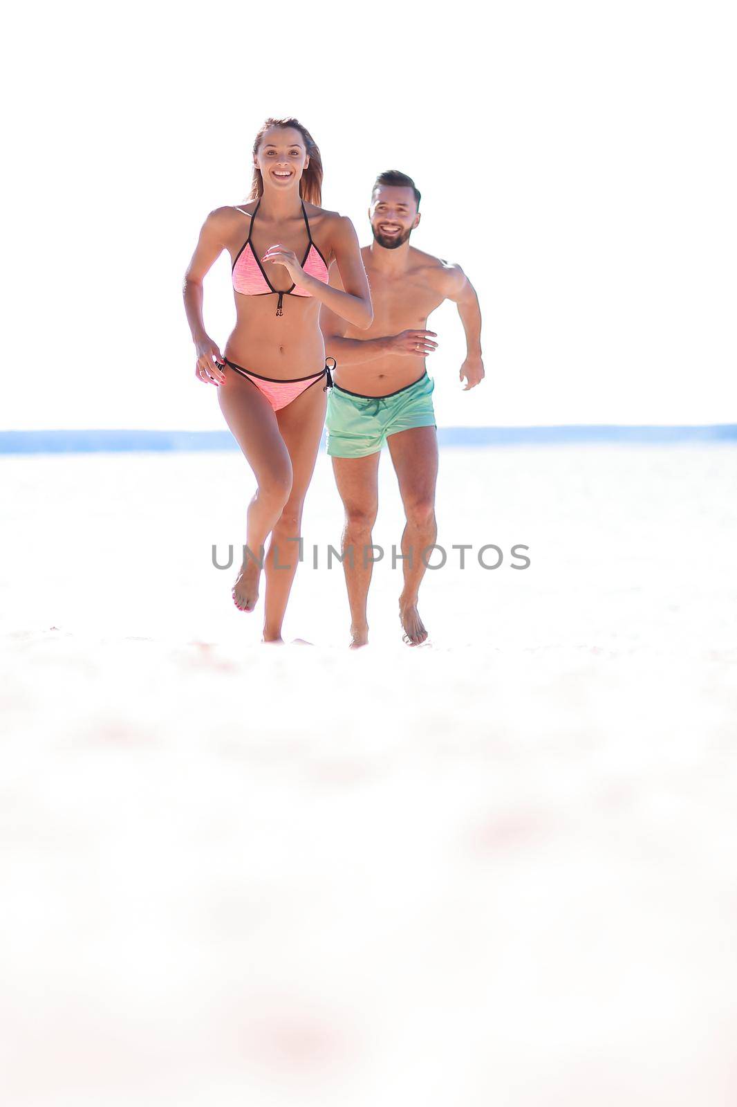 Couple having fun running throughsand on beach. by asdf