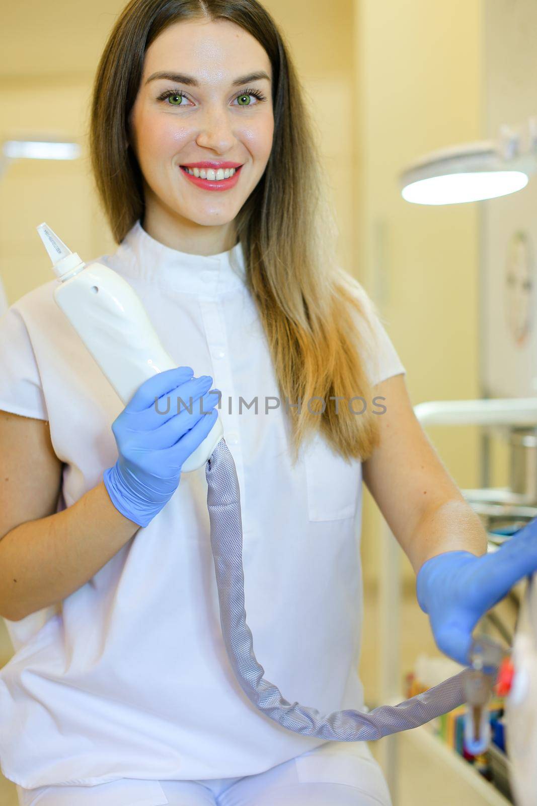 Young permanent makeup artist in special purpose glasses sitting with laser removal device at beauty salon. Concept of cosmetology equipment and cosmetologist.