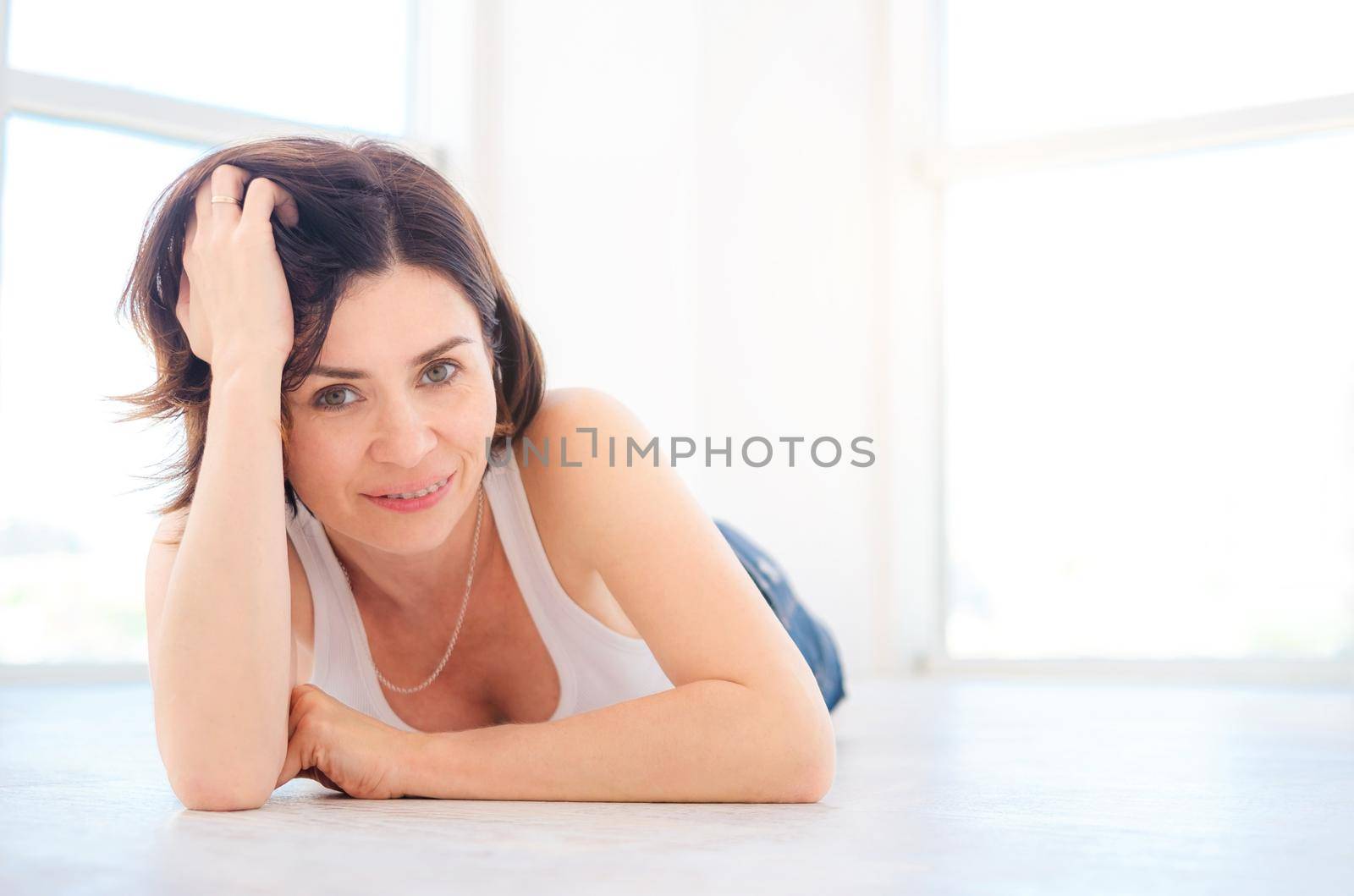 Beautiful young woman lying on a floor in light room