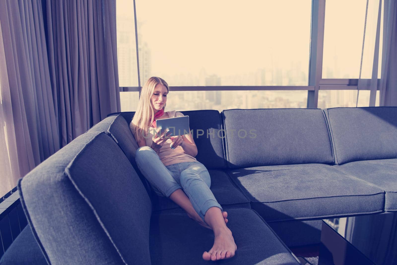 young woman on sofa at home surfing web by dotshock
