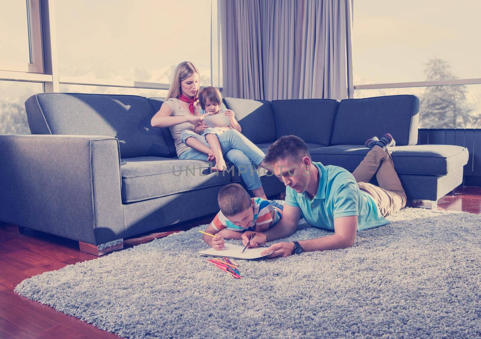 Happy Young Family Playing Together at home on the floor using a tablet and a children's drawing set