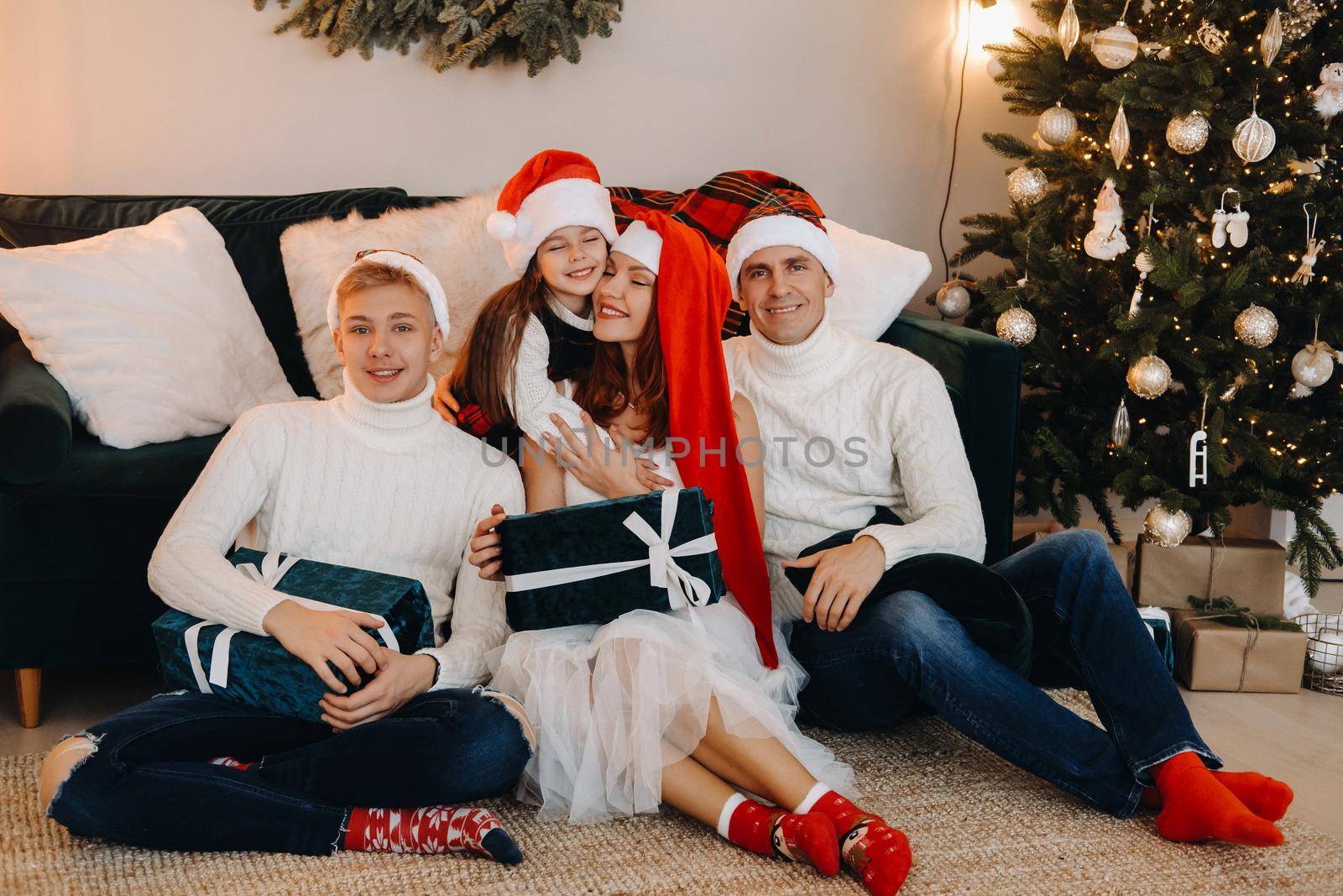 Close-up portrait of a happy family sitting on a sofa near a Christmas tree celebrating a holiday.