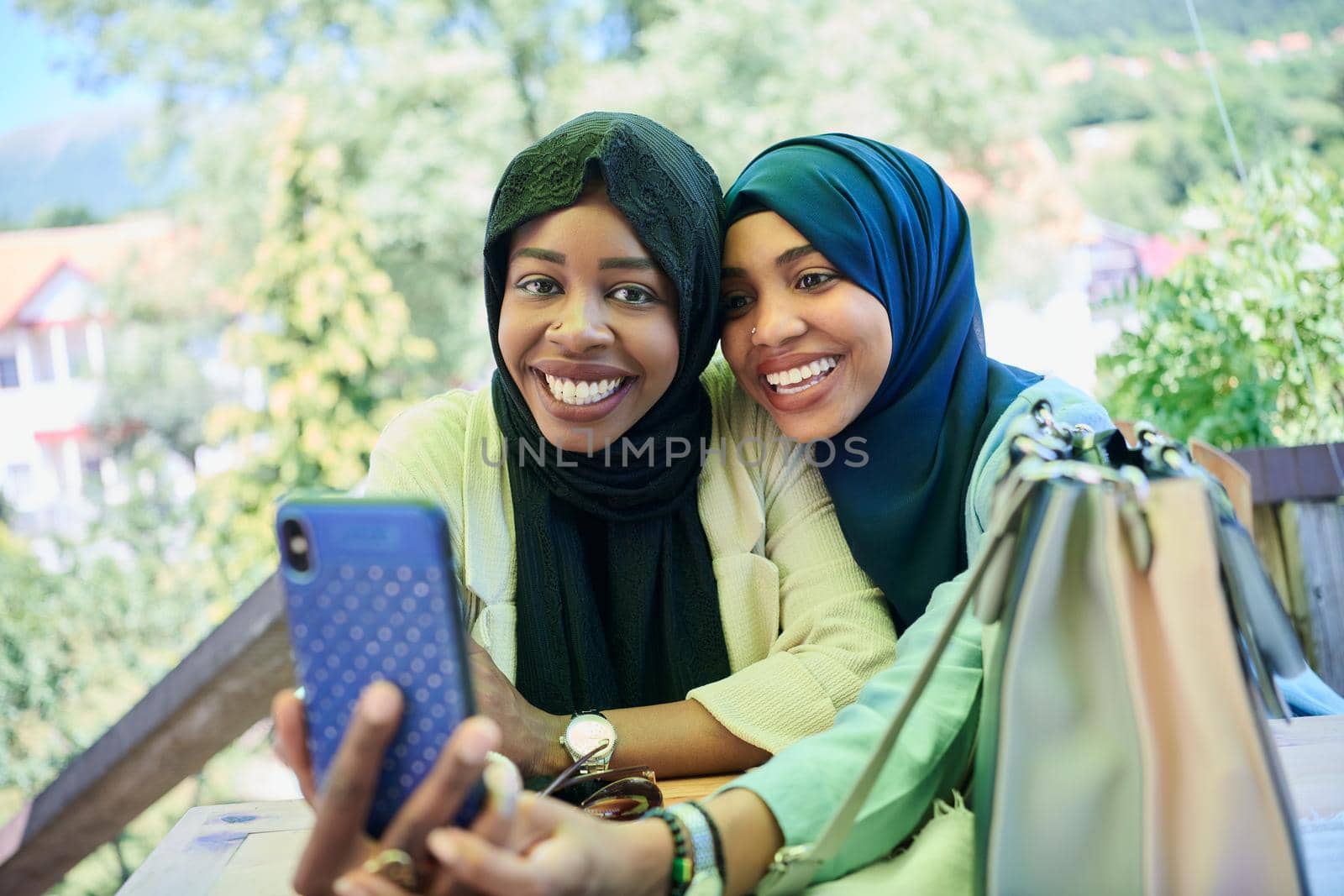 african female friends using smart phone together by dotshock