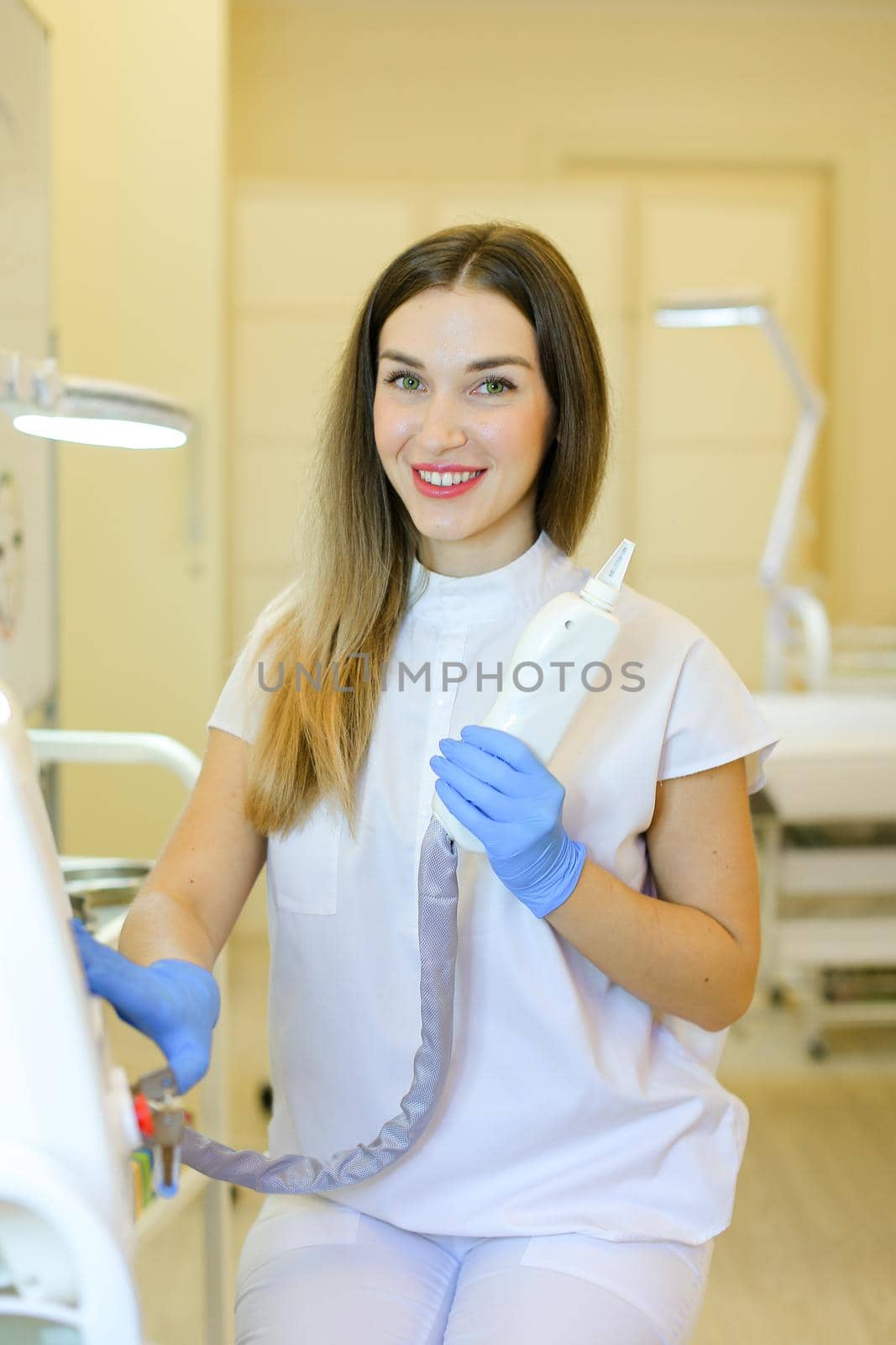 Young cosmetologist sitting with laser removal device at beauty salon. by sisterspro