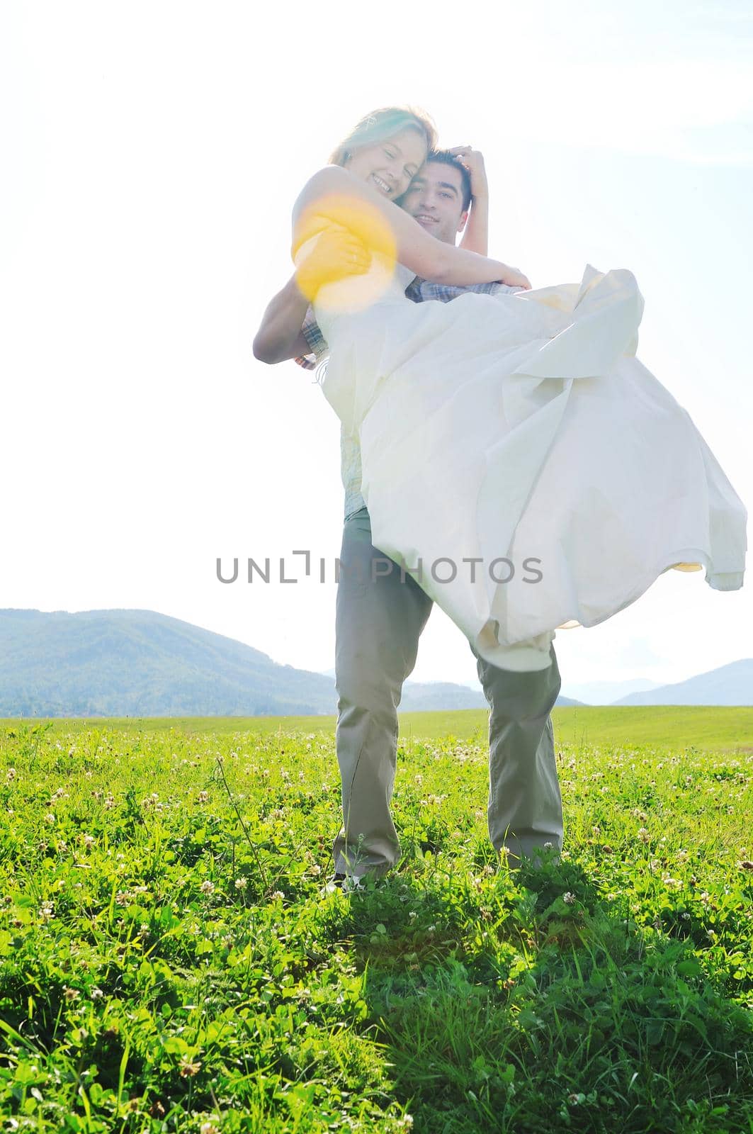 happy bride and groom walking and run on beautiful meadow outdoor at sunset